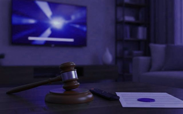 A judge gavel, a streaming remote and a sealed document on a coffee table in front of a TV